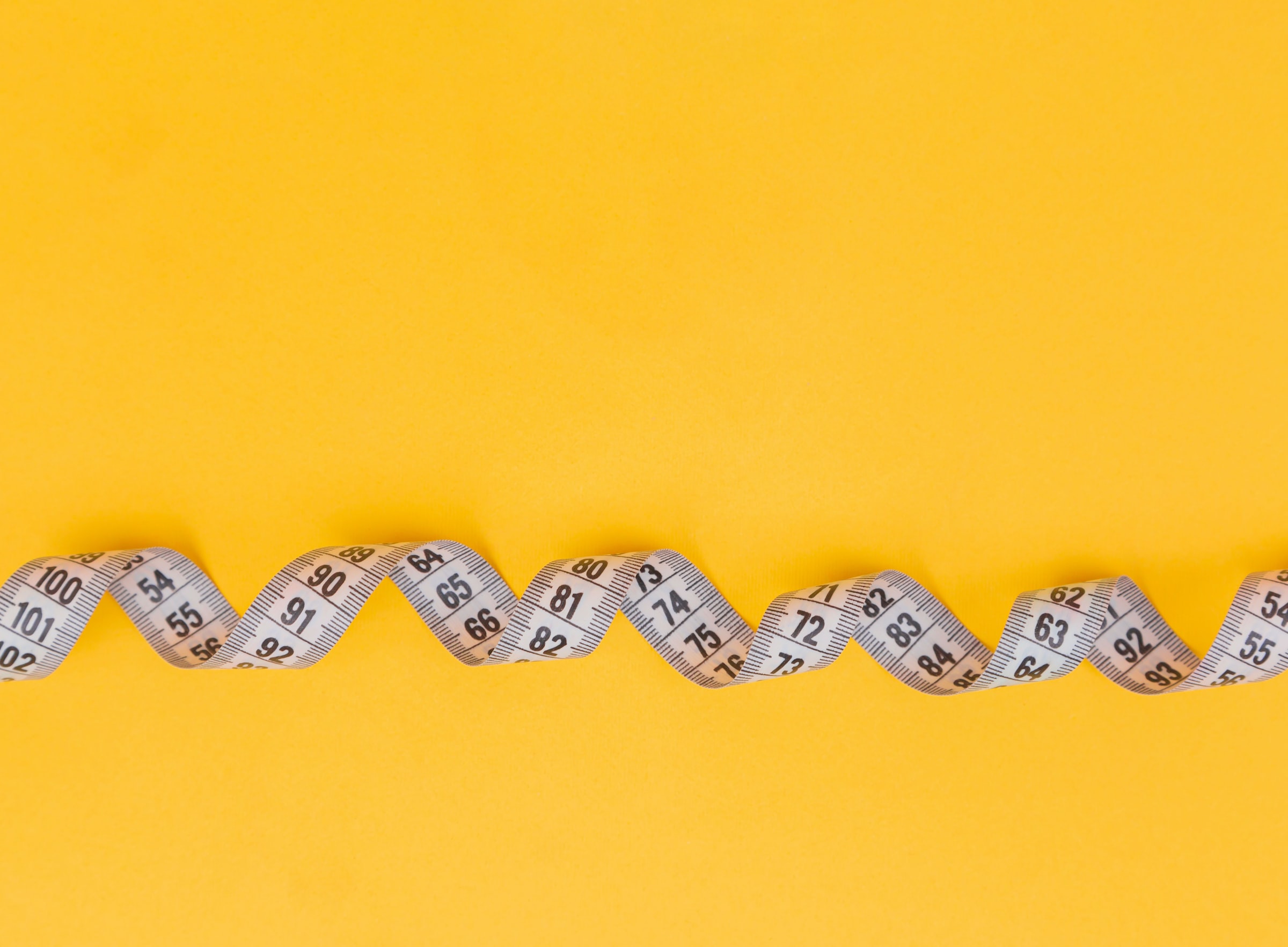 White tape measure on yellow background.